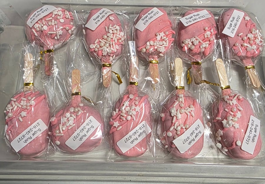 Tray of pink strawberry cakesicles with pearl sprinkles and Sugar Rush labels